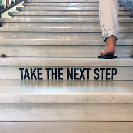 Take the next step sign on stairs